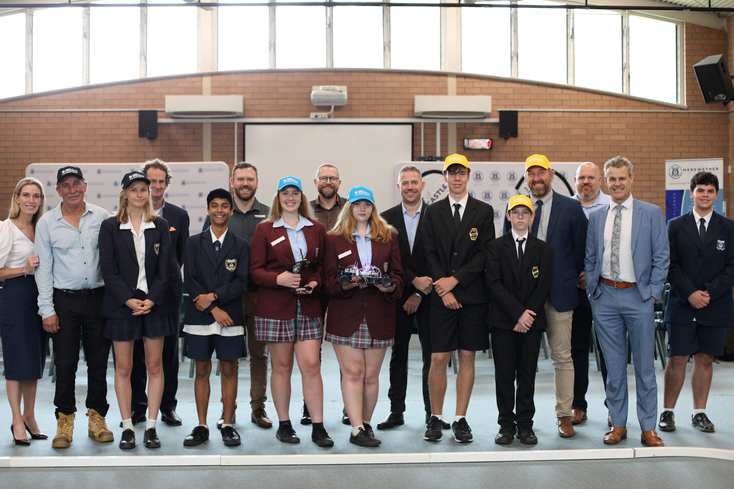 Group photo with students and partner participants in the H2 Grand Prix. Two female students stand at the front of the group holding a hydrogen remote controlled car.
